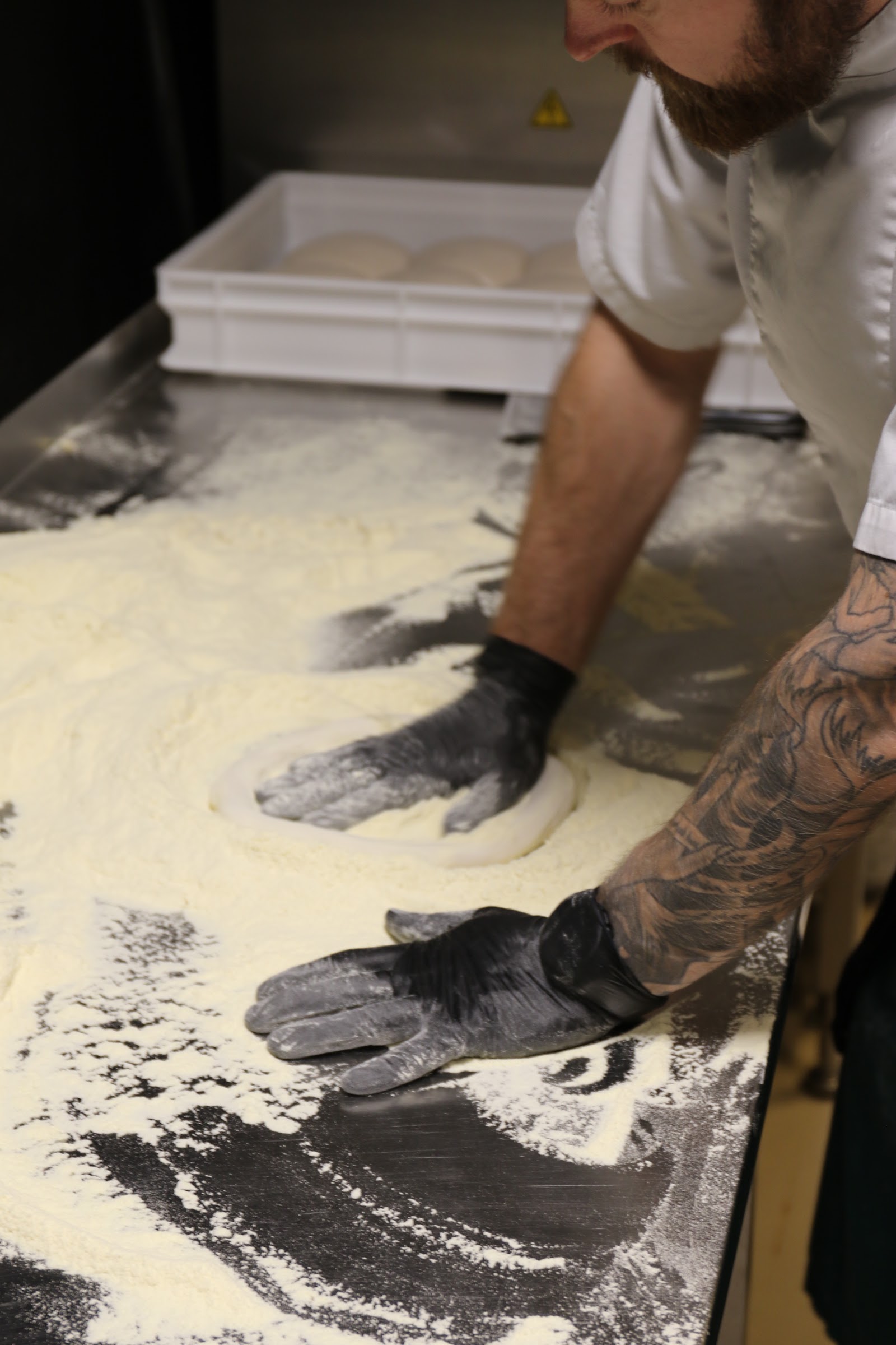 Pizzabaker som former deig på melet arbeidsbenk