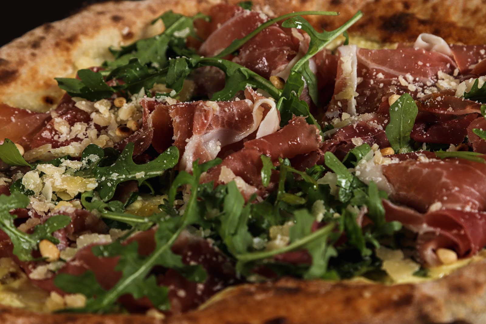 Nærbilde av pizza med parma, ruccola og parmesan